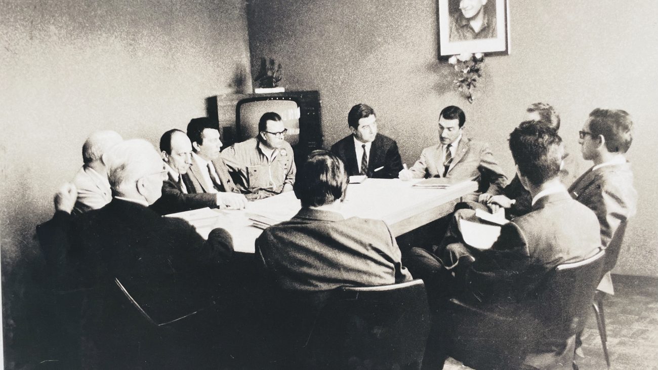 Historische Schwarzweiß-Aufnahme einer Besprechung im Ferrari-Büro der 1960er Jahre